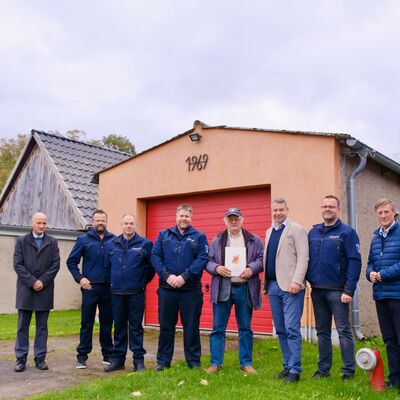 Foto 2: Landrat Michael Sack bei der &Uuml;bergabe des Zuwendungsbescheides an Medows B&uuml;rgermeister Hartmut P&auml;tzold (Mitte) im Beisein der Freiwilligen Feuerwehr und weiteren Beteiligten